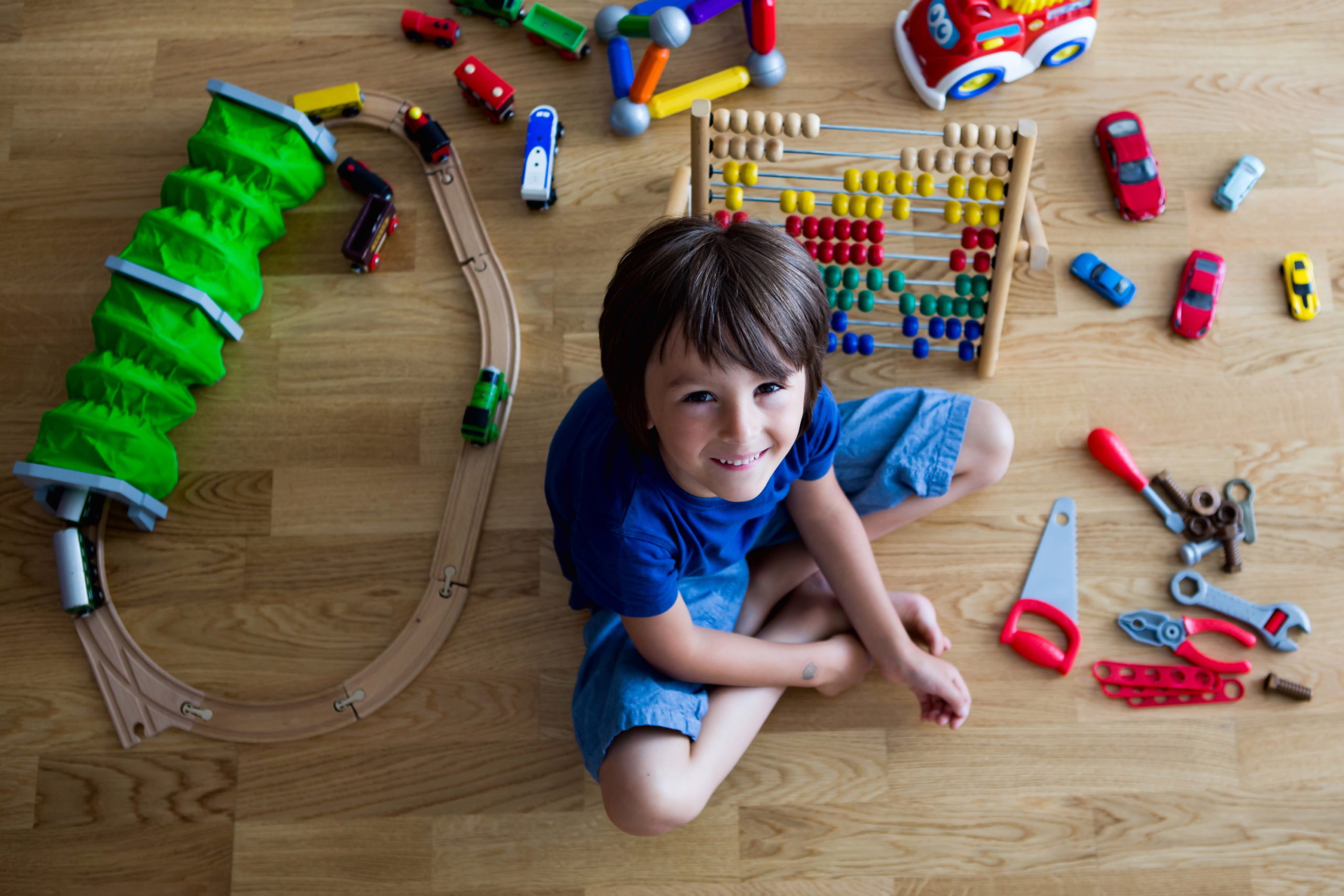 Junger Bursche spielt mit Spielzeug im Zimmer